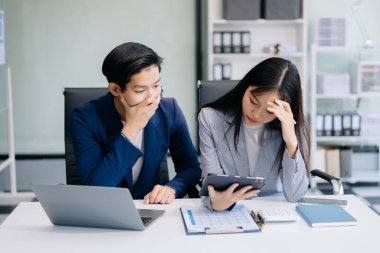 Öfkeli Asyalı iş adamları, modern ofiste bilgisayar ve tablet kullanarak bir hata yaptıktan sonra üzüldüler. 