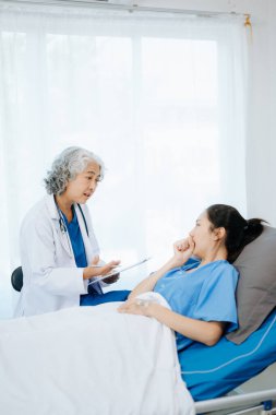  Doktor ve genç bayan hasta, doktor danışmanlık yaparken ve hastane koğuşlarında not alırken yatağa uzanıyorlar.