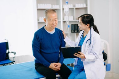 Beyaz takım elbiseli Asyalı doktor, hastanede ya da klinikte salin solüsyonu alan Asyalı yaşlıları ve yatakta yatan hastaları tartışırken not alıyor.