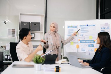Modern ofis binasında iş planlarını tartışan bir grup genç Asyalı iş adamı