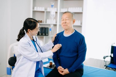 Beyaz elbiseli Asyalı doktor, Asyalı yaşlıları kontrol ediyor. Hastanede ya da klinikte tuz solüsyonu alan hasta.