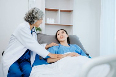  Doktor ve genç bayan hasta, hastane koğuşlarında steteskopla hastayı muayene ederken yatakta yatıyorlar.