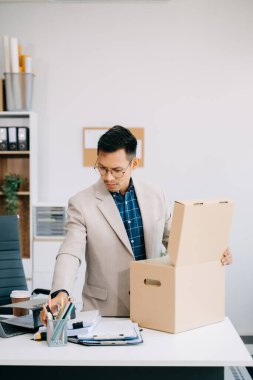 Asyalı ofis çalışanı, modern ofisteki işini bırakırken kişisel eşyalarını alıyor, ya da şirketini değiştiriyor.