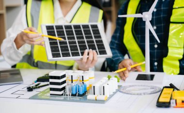 Asyalı iş adamları şirket ofisinde yeşil enerjili mimari proje sitesiyle ilgili danışmanlık yapıyorlar