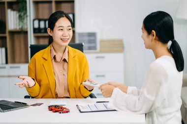 Asyalı kadın araba satıcısı Asyalı bir kadına araba satmayı teklif ediyor. Araba sözleşmesi imzalamayı ya da bir ofiste kira sözleşmesi imzalamayı açıklıyor. Kadın para verir ve araba alır. 