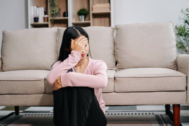 Asyalı kadın evdeki kanepede oturmuş depresyonda. 