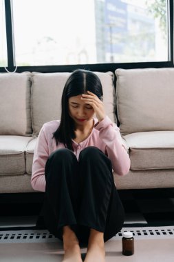 Asyalı kadın evdeki kanepede oturmuş depresyonda. 