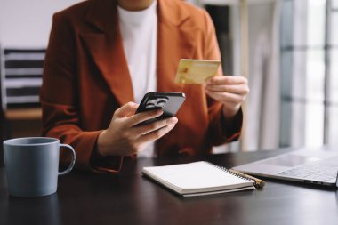Çevrimiçi alışveriş için akıllı telefon ve kredi kartı kullanan iş kadınının orta bölümü