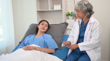 Kıdemli doktor, kadın hastayla yatakta konuşuyor.