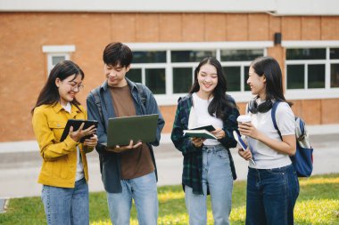 Üniversite öğrencileri sabahları kampüs parkında dijital tablet ve dizüstü bilgisayarla çalışıyorlar. 