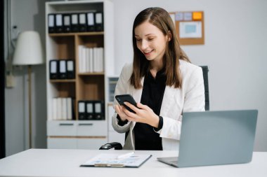 Akıllı telefon ve dizüstü bilgisayarla çalışan kendine güvenen iş uzmanı yaratıcı ofisteki masada. 