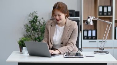 Ofiste çalışan Asyalı bir iş kadını ve dizüstü bilgisayar kullanıyor. 