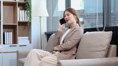 Asyalı iş kadını evde akıllı telefondan konuşuyor.