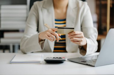 İş kadınının orta bölümü dizüstü bilgisayar kullanıyor ve online alışveriş için kredi kartı tutuyor.