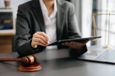 Adalet ve hukuk kavramı. Mahkeme salonundaki kadın yargıç tokmak, masada dijital tablet bilgisayarla çalışıyor.
