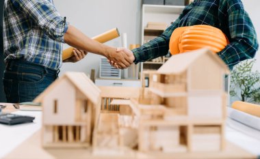 İnşaat ekibi el sıkışarak modern ofis merkezinde yeni proje planını başlatıyor. 