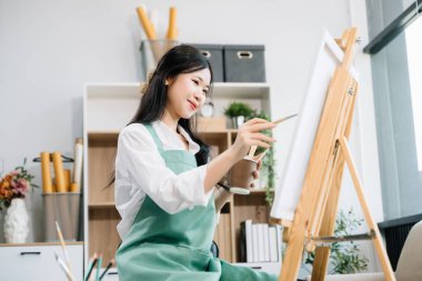 Sanat atölyesinde resim yapan Asyalı kadın ressam, boya malzemeleri, yağ boyaları, sanat stüdyosunda yaratıcı alan kullanıyor. 