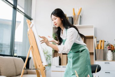 Sanat atölyesinde resim yapan Asyalı kadın ressam, boya malzemeleri, yağ boyaları, sanat stüdyosunda yaratıcı alan kullanıyor. 