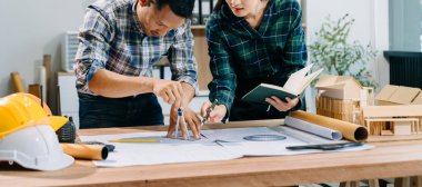 Asyalı mühendisler miğferler, planlar, ofis modelleri ile birlikte mimari projeler üzerinde tartışıyor ve birlikte çalışıyorlar. Modern ofiste Asya endüstrisi profesyonel takımı.