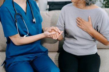 Genç hemşire yaşlı kadına yardım ediyor, el ele tutuşuyor, destek oluyor. Destekli yaşam tesisinde yaralanma üstüne tedavi ve rehabilitasyon
