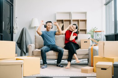 Büyük kutuları olan genç bir çift yeni bir eve taşınıyor ve kulaklıkla müzik dinliyor. 