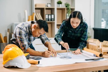 Mimari proje sahasında mühendislik ekibi çalışıyor ve modern ofiste model ev yapıyorlar. 