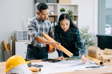 Mimari proje sahasında mühendislik ekibi çalışıyor ve modern ofiste model ev yapıyorlar. 