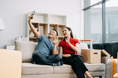 Büyük kutuları olan Asyalı genç ve çekici bir çift yeni bir eve taşınıyor ve akıllı telefondan selfie çekiyor. 