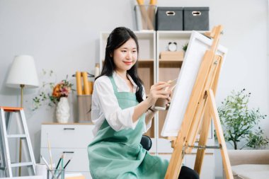 Sanat atölyesinde resim yapan Asyalı kadın ressam, boya malzemeleri, yağ boyaları, sanat stüdyosunda yaratıcı alan kullanıyor. 