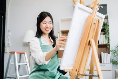 Sanat atölyesinde resim yapan Asyalı kadın ressam, boya malzemeleri, yağ boyaları, sanat stüdyosunda yaratıcı alan kullanıyor. 