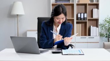 Ofisteki bir ofiste matematik finansmanı yapmak için dizüstü bilgisayarla not defteri yazan bir iş kadını.