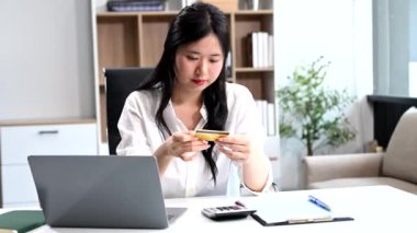 Ofiste matematik finansmanı yapan kredi kartı ve dizüstü bilgisayarı olan bir iş kadını.