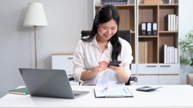 İş kadını ofisteki bir ofiste matematik finansmanı için telefon ve laptop kullanıyor.