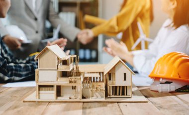 Mühendis ekibi proje inşaatı için çok çalışıyor, iş adamları el sıkışıyor. 