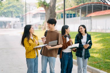 Üniversite öğrencileri sabahları kampüs parkında dijital tablet ve dizüstü bilgisayarla çalışıyorlar. 
