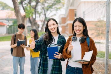 Üniversite öğrencileri sabahları kampüs parkında dijital tabletle ders çalışıyor.