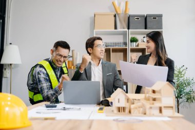 Mühendis takımları mimari proje sahasında birlikte çalışarak model ev yapıyorlar. Modern ofiste Asya endüstrisi profesyonel takımı