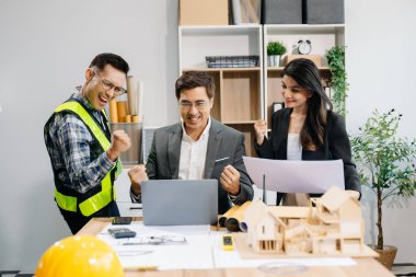Mühendis takımları mimari proje sahasında birlikte çalışarak model ev yapıyorlar. Modern ofiste Asya endüstrisi profesyonel takımı