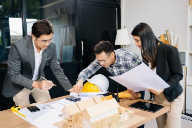 Mühendis takımları mimari proje sahasında birlikte çalışarak model ev yapıyorlar. Modern ofiste Asya endüstrisi profesyonel takımı