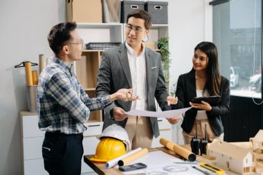 Mühendis takımları mimari proje sahasında birlikte çalışarak model ev yapıyorlar. Modern ofiste Asya endüstrisi profesyonel takımı