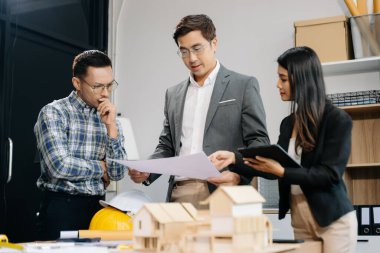 Mühendis takımları mimari proje sahasında birlikte çalışarak model ev yapıyorlar. Modern ofiste Asya endüstrisi profesyonel takımı