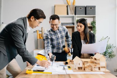 Mühendis takımları mimari proje sahasında birlikte çalışarak model ev yapıyorlar. Modern ofiste Asya endüstrisi profesyonel takımı