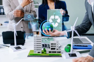 İş adamlarının şirket ofisinde rüzgar enerjisi hakkında görüşleri var. Yel değirmenleri ve alternatif yeşil enerji hakkında tartışan iş ekibi, dizüstü bilgisayar ve tablet kullanarak