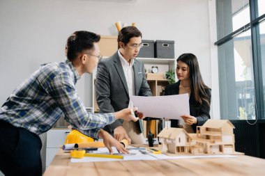 Mühendis takımları mimari proje sahasında birlikte çalışarak model ev yapıyorlar. Modern ofiste Asya endüstrisi profesyonel takımı