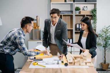 Mühendis takımları mimari proje sahasında birlikte çalışarak model ev yapıyorlar. Modern ofiste Asya endüstrisi profesyonel takımı