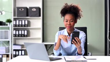 Modern ofis masasında telefon ve dizüstü bilgisayarla finans analizi yapan başarılı bir iş kadını. 