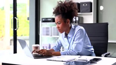 Ofiste çalışmak için dizüstü bilgisayar kullanan kendine güvenen Afro-Amerikan iş kadını. 