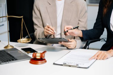 İş adamları ve avukatlar ofiste kontrat belgelerini tartışıyorlar ve dizüstü bilgisayar ve tablet kullanıyorlar. Hukuk ve adalet kavramı 