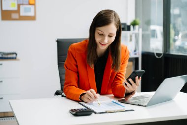 İş kadını ofisteki masada dizüstü bilgisayar ve yazılı belgeler kullanıyor. 