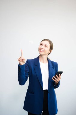 Akıllı telefon kullanan ve beyaz arka planda izole edilmiş bir parmak gösteren kendine güvenen beyaz iş kadını.